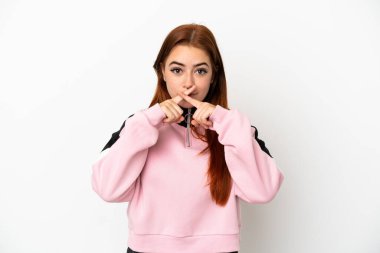 Beyaz arka planda izole edilmiş genç kızıl saçlı kadın sessizlik işareti gösteriyor.