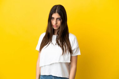 Sarı arka planda, üzgün bir ifadeyle izole edilmiş beyaz bir kadın.