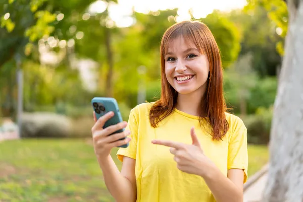 Giovane Bella Rossa Donna All Aperto Utilizzando Telefono Cellulare Indicandolo — Foto Stock