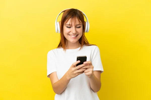 Redhead Κορίτσι Απομονώνονται Κίτρινο Φόντο Ακούγοντας Μουσική Ένα Κινητό Και — Φωτογραφία Αρχείου