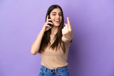 Mor arka planda izole edilmiş cep telefonu kullanan beyaz bir kadın geliyor.