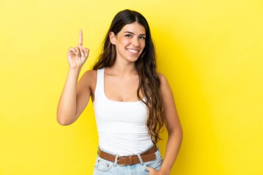 Sarı arka planda izole edilmiş beyaz bir kadın harika bir fikre işaret ediyor.