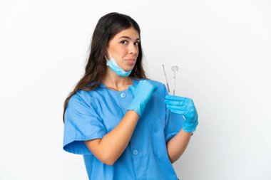 Dişçi kadın kendini beğenmiş ve gururlu beyaz bir arkaplan üzerinde aletler tutuyor.