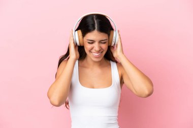 Pembe arka planda izole edilmiş beyaz bir kadın müzik dinliyor.