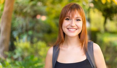 Genç, güzel, kızıl saçlı, açık havada mutlu bir yüzü olan bir kadın.