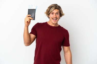 Beyaz arka planda izole edilmiş genç sarışın adam tatilde mutlu bir şekilde pasaport ve uçak biletleriyle.