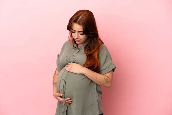 若いですRedhead Caucasian女性隔離上のピンクの背景妊娠 — ストック写真