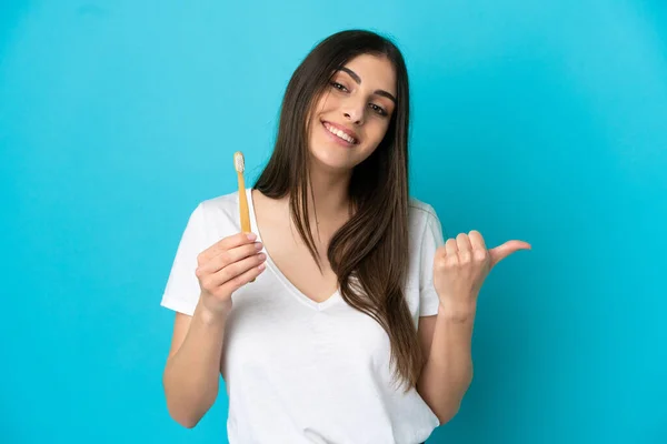 Młoda Biała Kobieta Myje Zęby Wyizolowane Niebieskim Tle Wskazując Bok — Zdjęcie stockowe