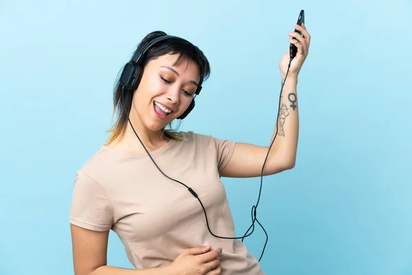 Νεαρή Ουρουγουανή Κοπέλα Πάνω Από Απομονωμένο Μπλε Φόντο Ακούγοντας Μουσική — Φωτογραφία Αρχείου