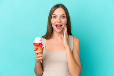 Kornet dondurmalı genç Litvanyalı kadın mavi arka planda, şaşırmış ve şok olmuş bir yüz ifadesiyle izole edilmiş.