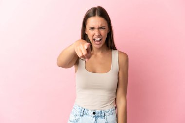 Soyutlanmış pembe arka planı olan genç bir kadın hayal kırıklığına uğramış ve ön tarafı işaret ediyor.