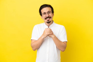 Sarı arka planda izole edilmiş genç beyaz adam gülüyor.