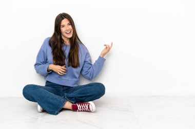 Genç bir kadın yerde oturmuş gitar hareketi yapıyor.