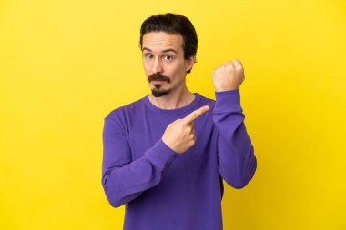 Sarı arka planda izole genç beyaz adam geç kalma jesti yapıyor