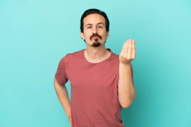 Mavi arka planda izole edilmiş genç beyaz adam İtalyan jestleri yapıyor.