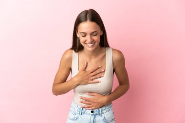 Soyutlanmış pembe arka planı olan genç bir kadın çok gülümsüyor.