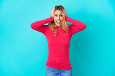 Sürpriz ifade ile izole mavi arka plan üzerinde genç kadın