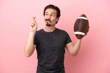 Rugby oynayan beyaz bir adam pembe arka planda izole edilmiş, şans diliyor.