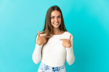 Soyutlanmış mavi arka planı olan genç bir kadın. Şaşırtıcı bir yüz ifadesi.