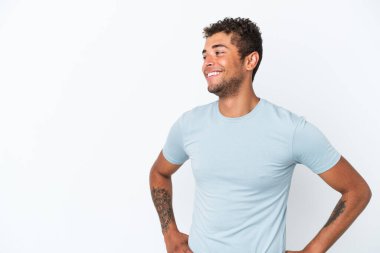 Beyaz arka planda izole edilmiş, kolları kalçasında ve gülümseyen genç, yakışıklı Brezilyalı bir adam.