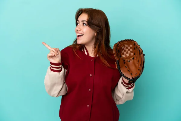 指を持ち上げながら解決策を実現しようと青い背景に隔離された野球をしている若い赤毛の女性 — ストック写真