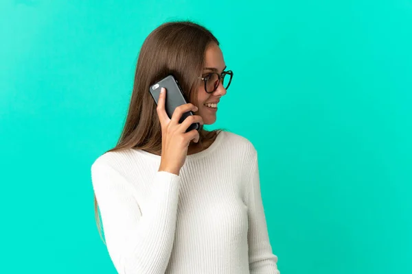Молодая Женщина Изолированном Синем Фоне Ведет Разговор Кем Мобильному Телефону — стоковое фото
