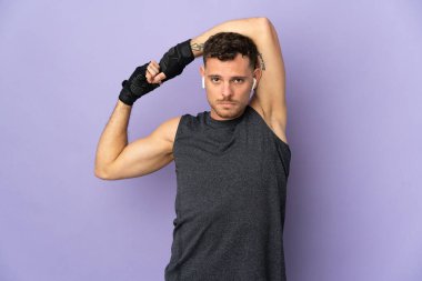 Mor arka planda izole edilmiş, kollarını esneten beyaz, yakışıklı genç bir adam.