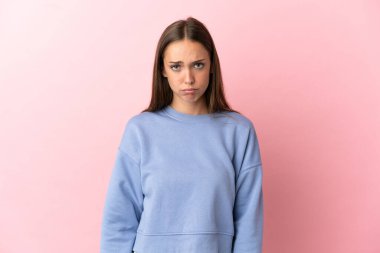 Hüzünlü bir ifadeyle soyutlanmış pembe arka planı olan genç bir kadın