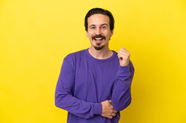 Sarı arka planda izole edilmiş genç beyaz adam gülüyor.