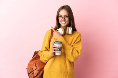 Tecrit edilmiş pembe arka planı olan genç bayan bir ürünü sunmak için kenarı işaret ediyor.