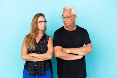 Mavi arka planda izole edilmiş orta yaşlı bir çift öfkeli bir hareketle sinirlendi.