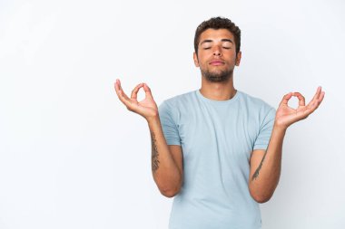 Genç ve yakışıklı Brezilyalı bir adam Zen pozunda beyaz arka planda izole edilmiş.