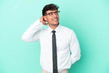 Kafkasyalı iş adamı mavi arka planda izole edilmiş bir fikir düşünüyor.