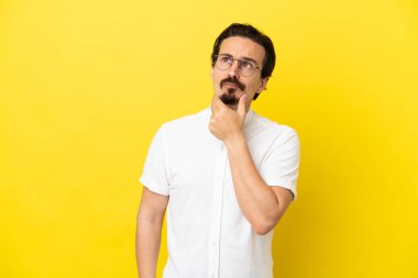 Sarı arka planda izole edilmiş genç beyaz adamın şüpheleri var.