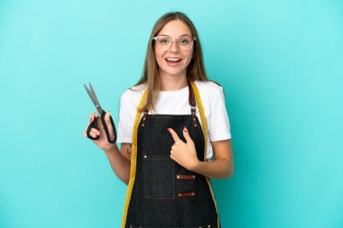 Genç Litvanyalı terzi kadın mavi arka planda yalıtılmış ve yüzünde sürpriz bir ifade var.