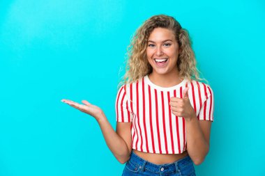 Kıvırcık saçlı kız mavi arka planda izole edilmiş. Kopyalama alanı hayali bir şey tutuyor. İlan vermek için.