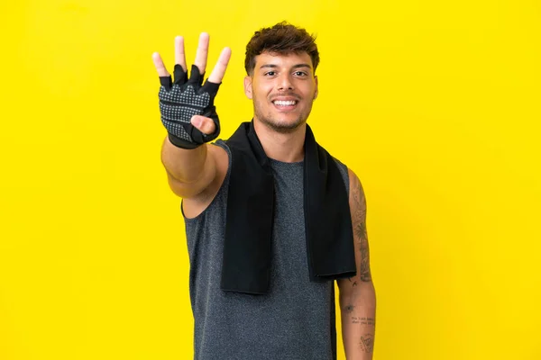 年轻的体育白人男子与毛巾隔离黄色背景快乐和计数四个手指 — 图库照片