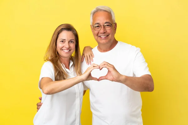 Ζευγάρι Μέσης Ηλικίας Απομονωμένο Κίτρινο Φόντο Κάνοντας Μια Καρδιά Χέρια — Φωτογραφία Αρχείου
