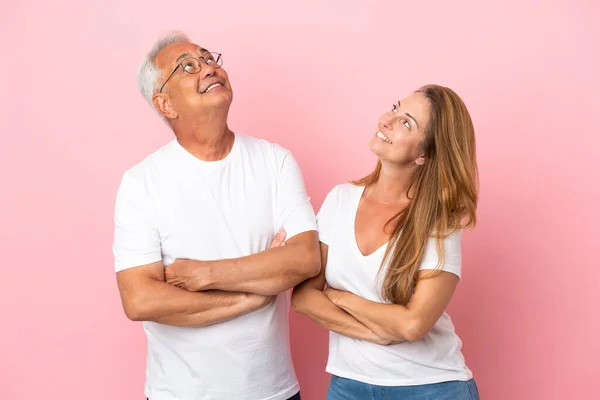 Middelaldrende Par Isolert Rosa Bakgrunn Ser Opp Mens Smiler – stockfoto