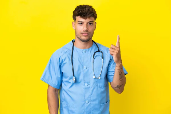 若いです外科医男隔離上の黄色の背景ポインティングとともにザインデックス指素晴らしいアイデア — ストック写真