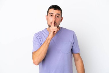 Beyaz arka planda izole edilmiş yakışıklı beyaz adam sessiz bir jest işareti gösteriyor. Parmağını ağzına sokuyor.