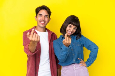 Sarı arka planda soyutlanmış genç melez bir çift birlikte gelmeye davet ediyor. Gelmene sevindim.