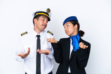 Uçak pilotu ve karışık yarış hostesi beyaz arka planda izole edilmiş, omuzlarını kaldırırken önemsiz bir jest yapıyorlar.