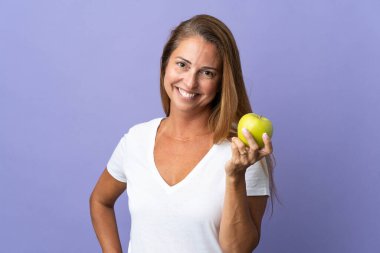 Orta yaşlı Brezilyalı kadın mor arka planda elma ile izole edilmiş.