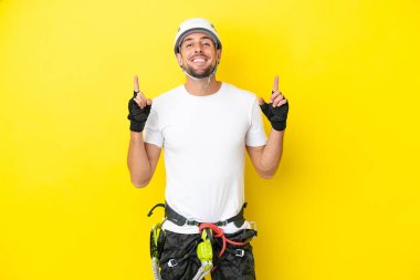 Genç kaya tırmanıcısı sarı arka planda izole edilmiş harika bir fikre işaret ediyor.