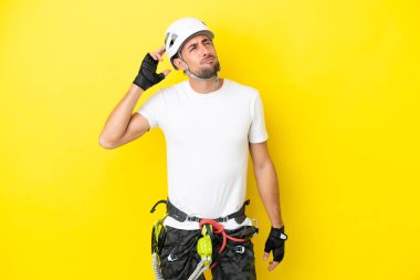 Sarı arka planda izole edilmiş genç kaya tırmanışçısının şüpheleri ve kafa karıştırıcı bir yüz ifadesi var.