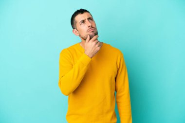 Mavi arka planda izole edilmiş yakışıklı beyaz adam kuşkuları var.