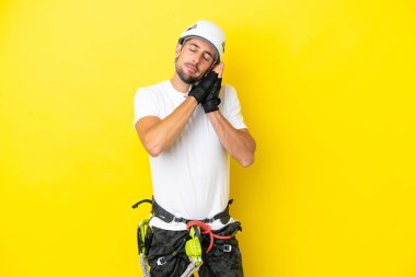 Sarı arka planda izole edilmiş genç kaya tırmanışçısı, hareketsiz bir uyku hareketi yapıyor.