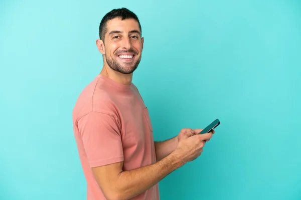 Mavi Arka Planda Izole Edilmiş Yakışıklı Beyaz Adam Cep Telefonuyla — Stok fotoğraf