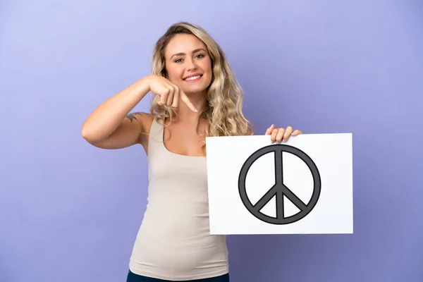 Молода Бразилька Ізольована Пурпуровому Фоні Тримає Плакат Символом Миру Вказує — стокове фото